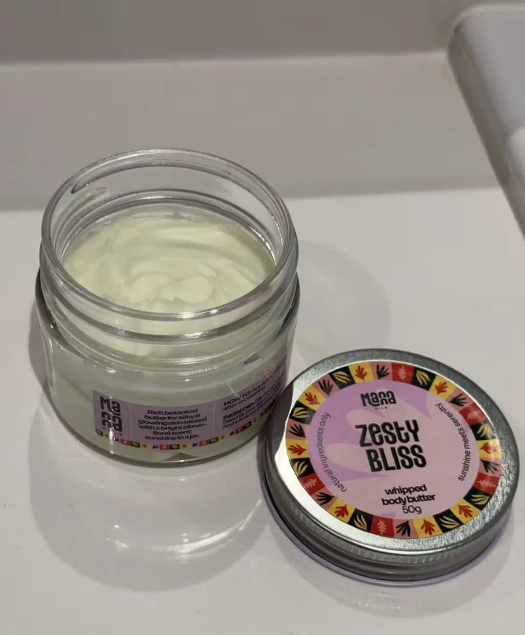 Amir Salman's open jar of Manna Zesty Bliss body butter beside its lid
